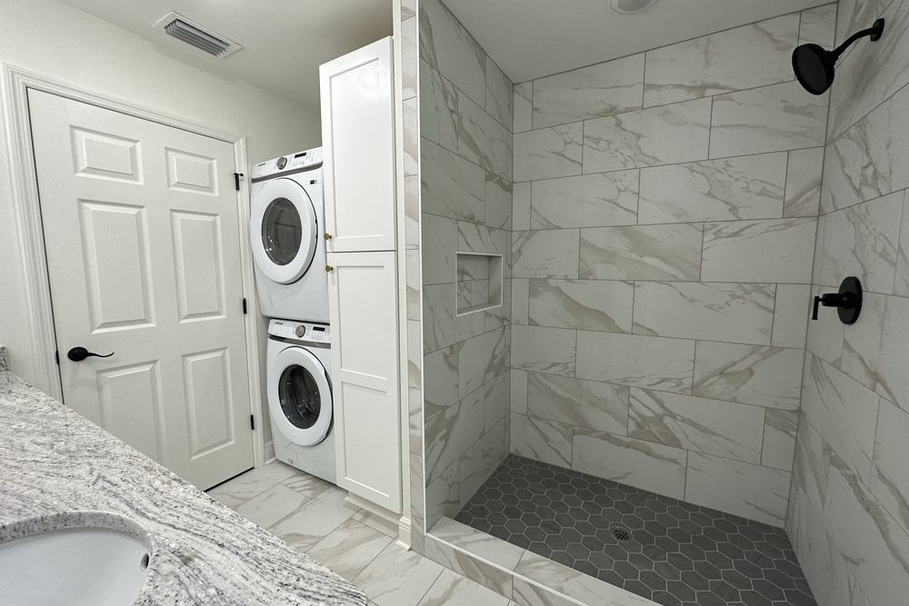 Cottage ADU bathroom with a tiled shower and stacked laundry