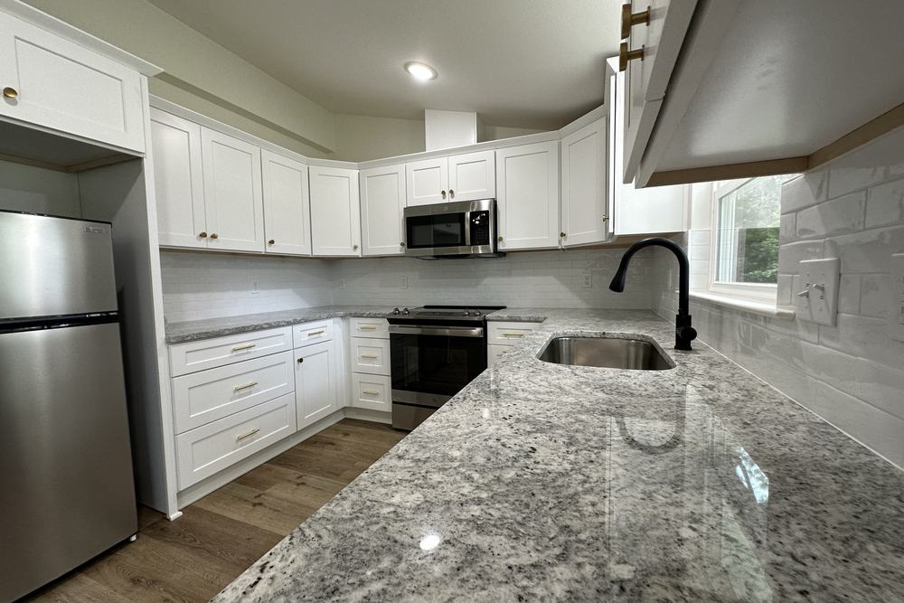 Cottage ADU kitchen with white cabinets and granite countertops