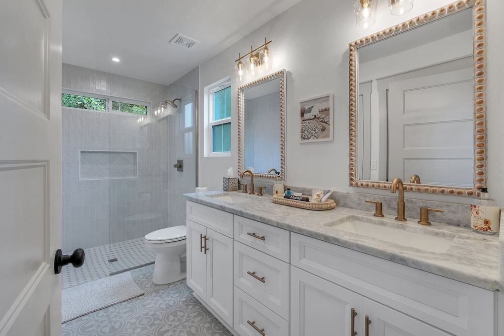Bathroom with a walk-in tiled shower, granite vanity and brass fixtures