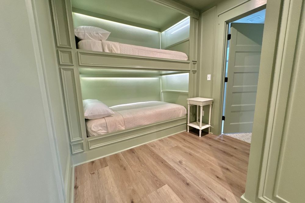 Built-in bunk room painted sage green with recessed lighting