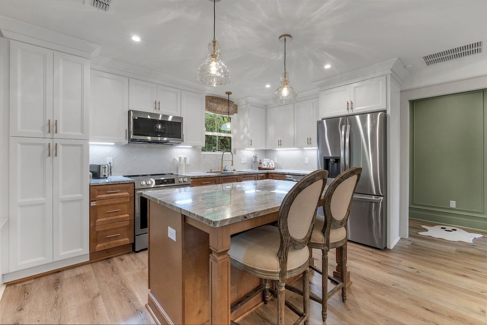 Full kitchen with a granite island, pendant lighting and stainless appliances