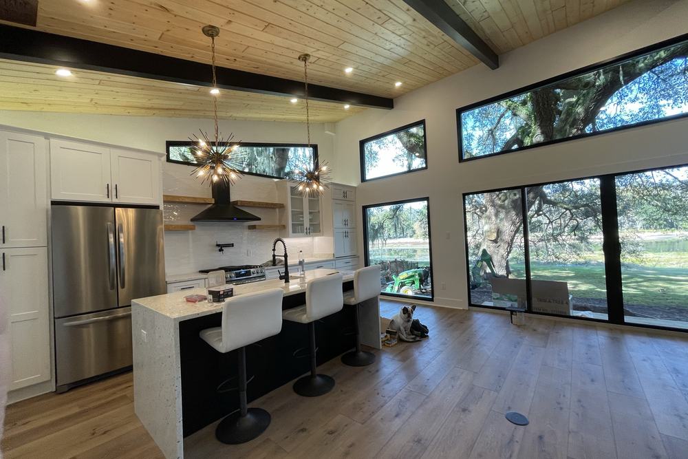 ADU kitchen with an island, stained wood ceiling and a wall of glass