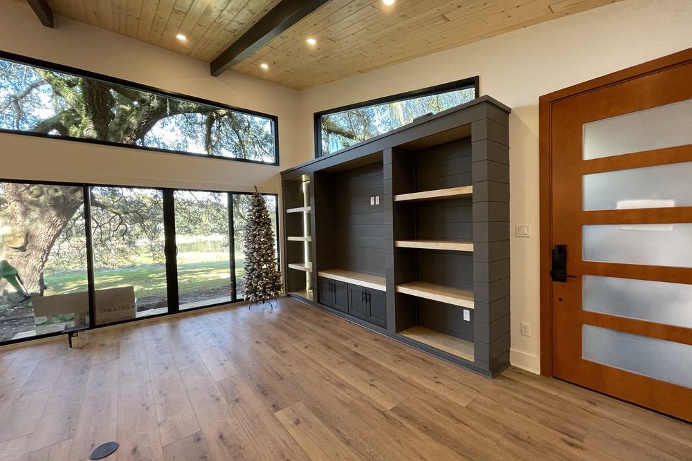 Living area with clerestory windows, built-in shelving and a custom wood door