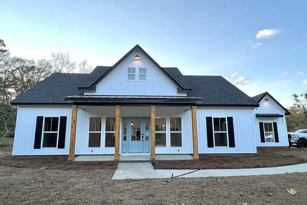 New construction farmhouse with a dark standing-seam roof and covered porch