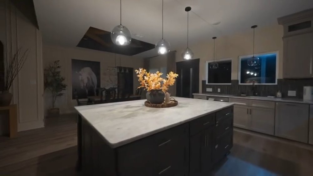 Kitchen with dark cabinetry, a waterfall stone island and pendant lighting, built by JSR Construction