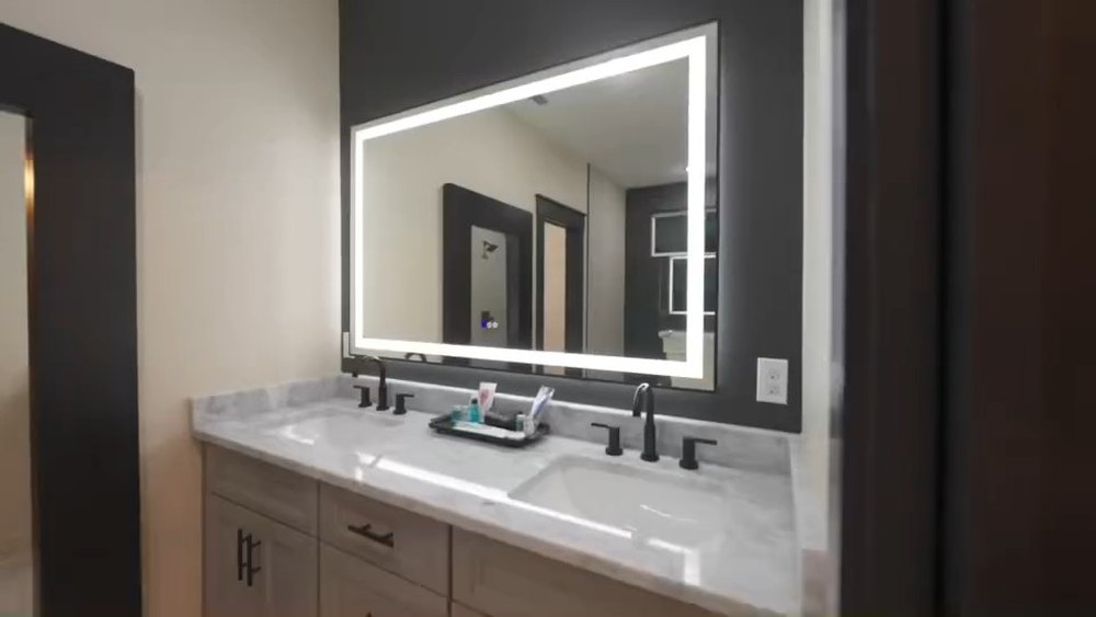 Double vanity with a backlit LED mirror and stone countertop