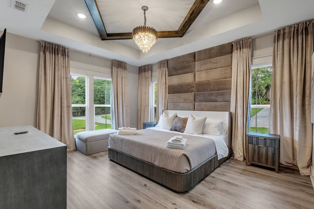 Primary bedroom with a tray ceiling and a wood feature wall