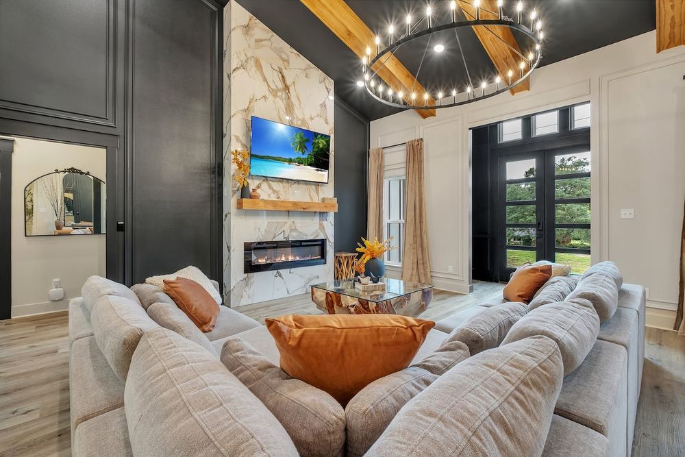Living room with a marble fireplace, ring chandelier and black feature wall