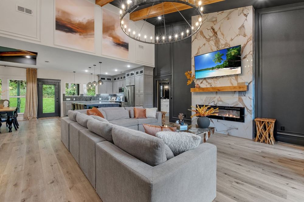 Open living and kitchen with exposed beams and a linear fireplace