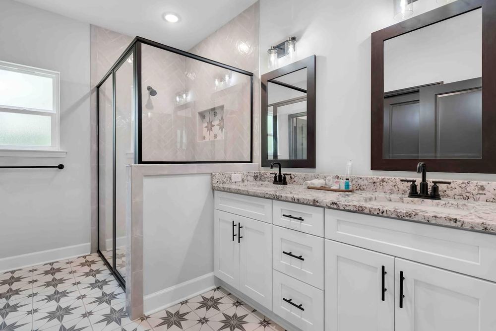 Bathroom with a double vanity, patterned tile floor and a glass shower