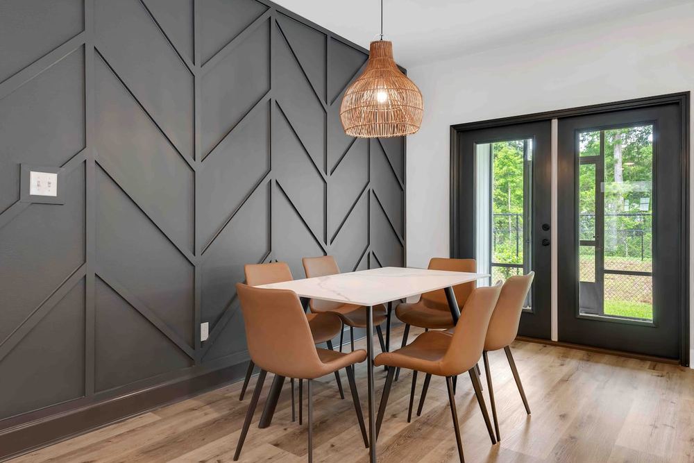 Dining area with a geometric panelled accent wall and black french doors
