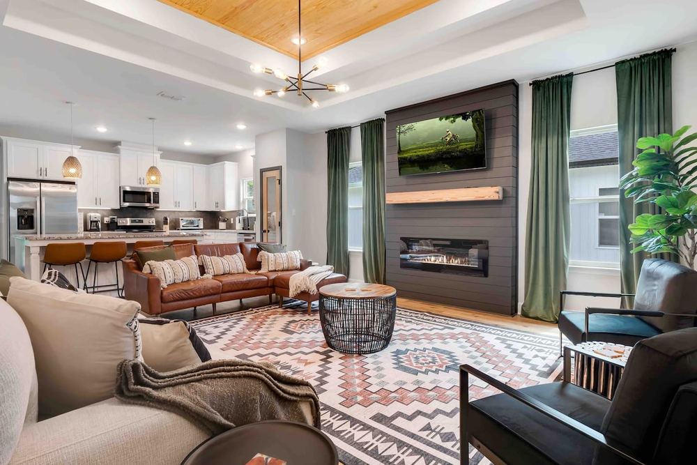 Living room with a linear fireplace and a stained wood tray ceiling