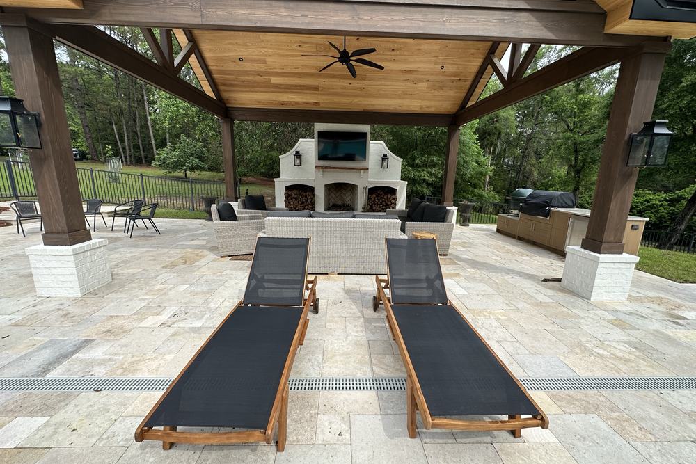 Travertine pool deck looking toward a covered outdoor fireplace