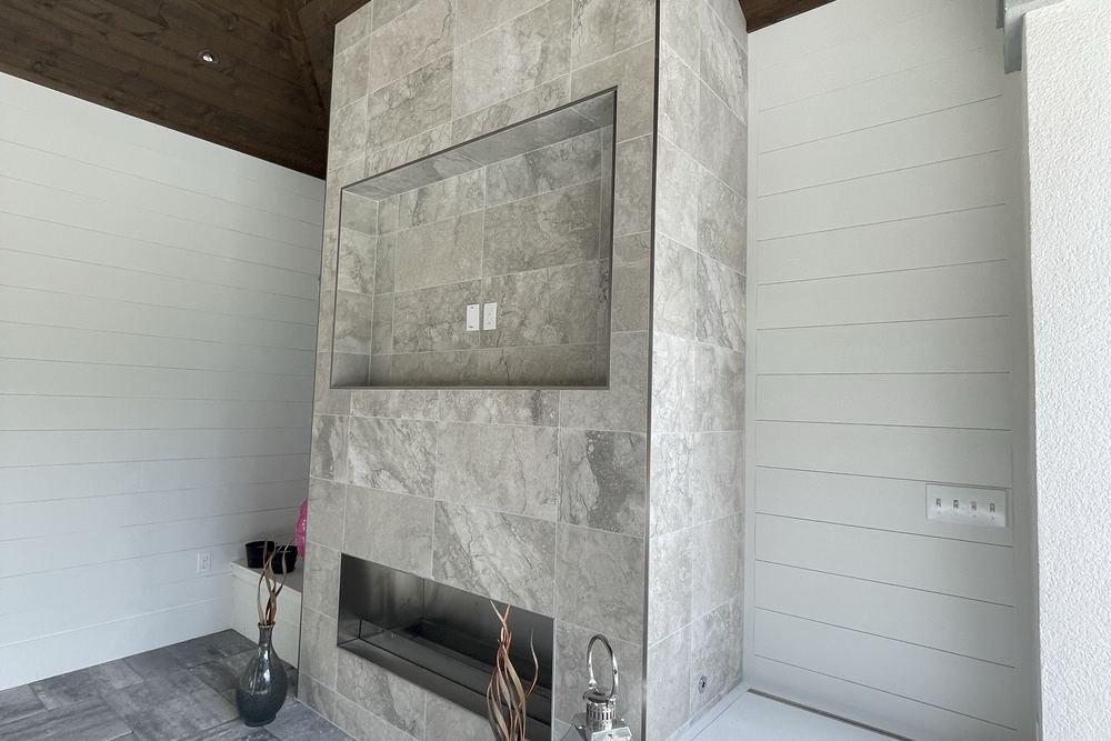 Marble-clad outdoor fireplace with a linear firebox and herringbone travertine floor